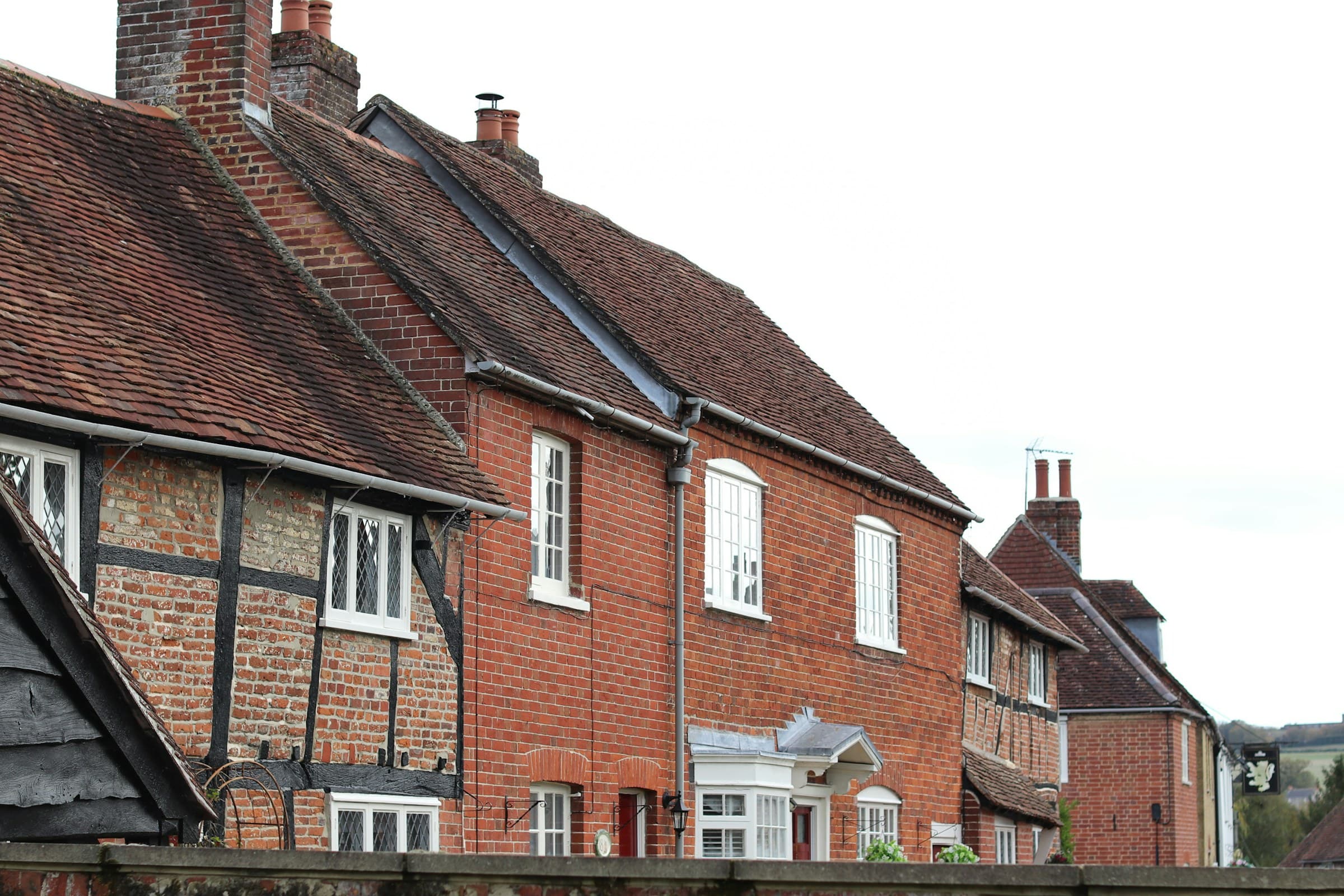 A row of traditional brick houses with aged tiled roofs, the facades pointed in lime mortar with historic rainwater goods and weathered signage.