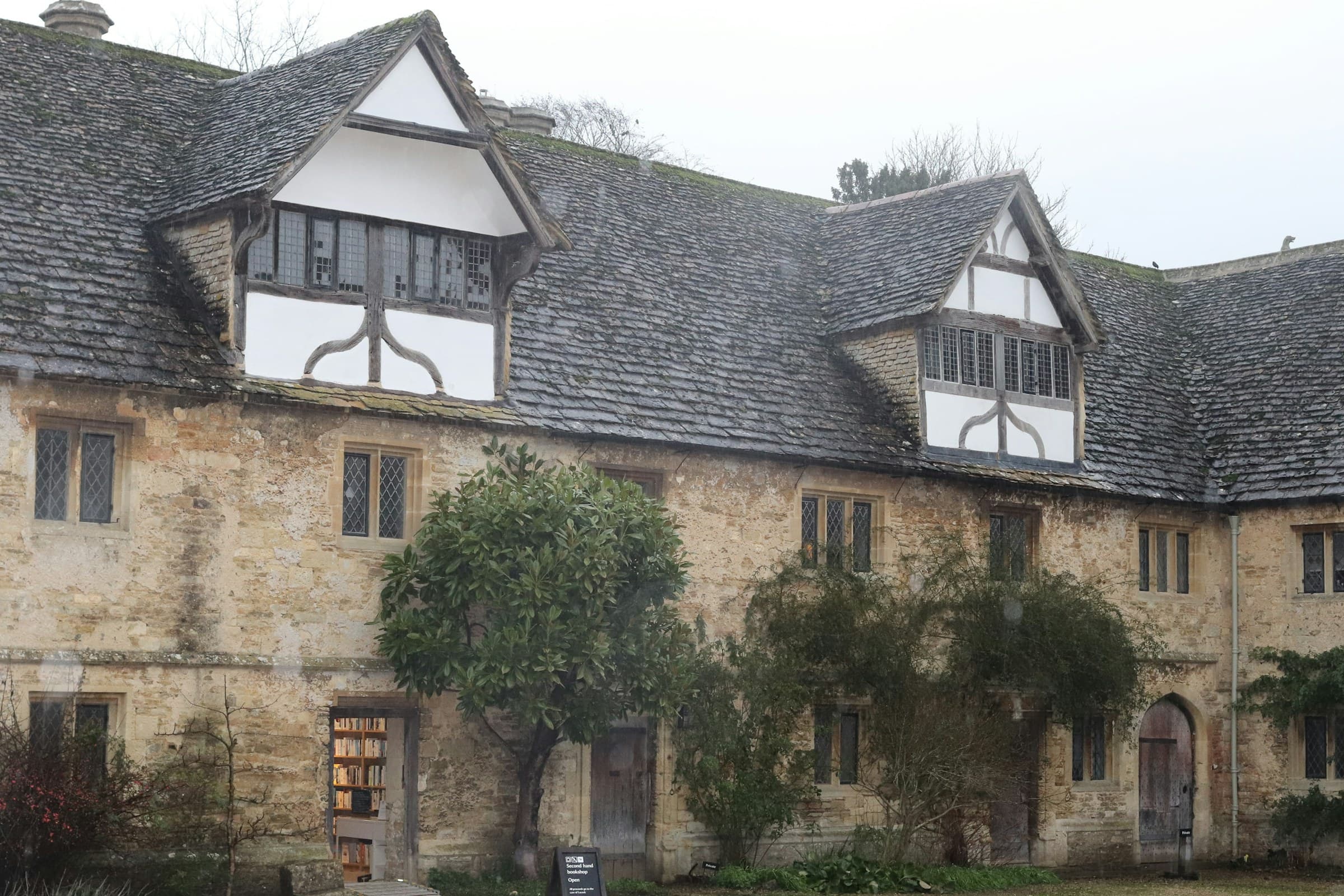 An old stone farmhouse with timber framing and dormer windows set in a quiet rural landscape, with the lime-pointed stonework catching soft daylight.