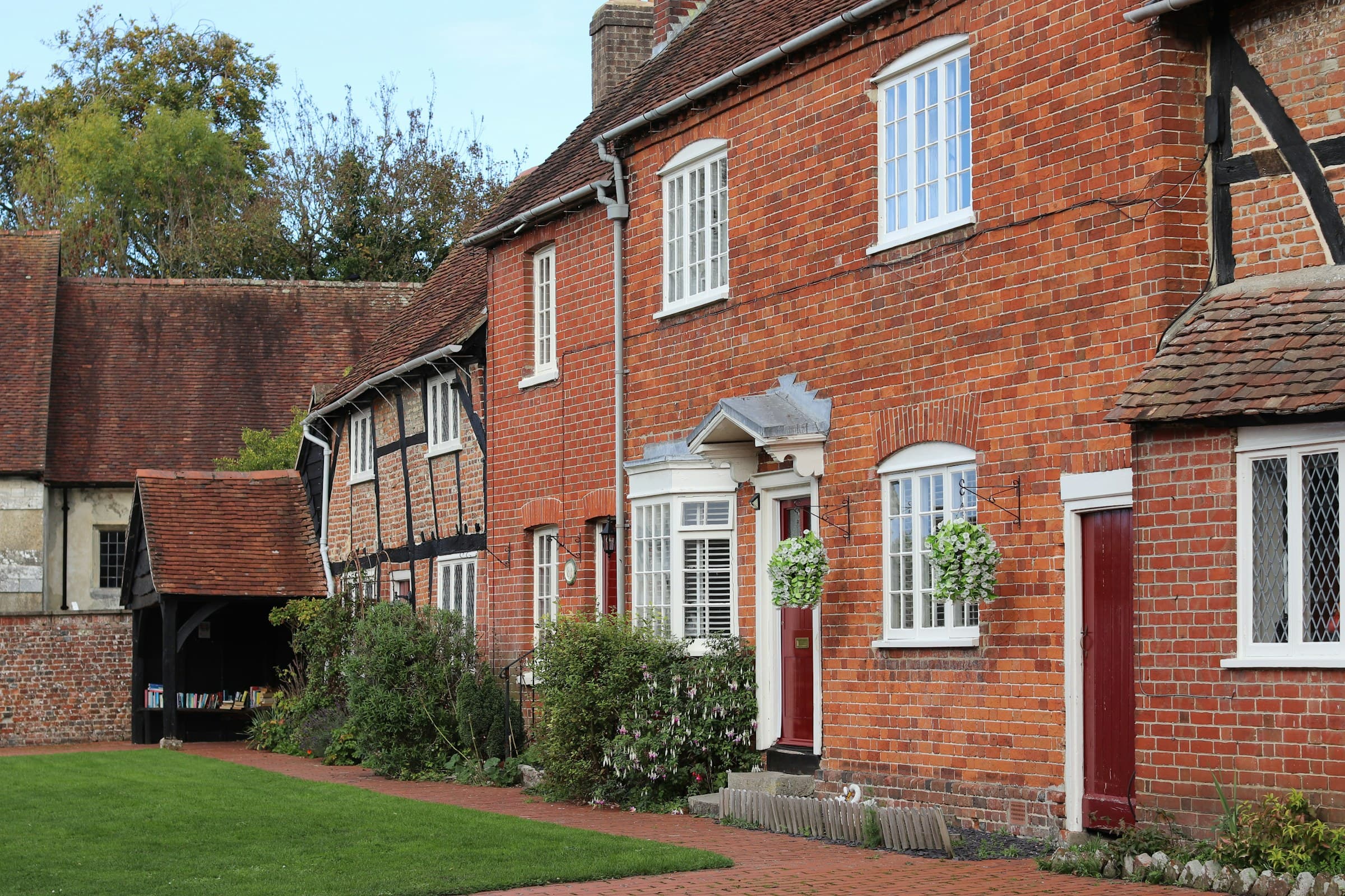 A row of traditional brick and timber-framed houses standing shoulder to shoulder on a historic English street, with exposed oak framing and lime-washed infill panels.